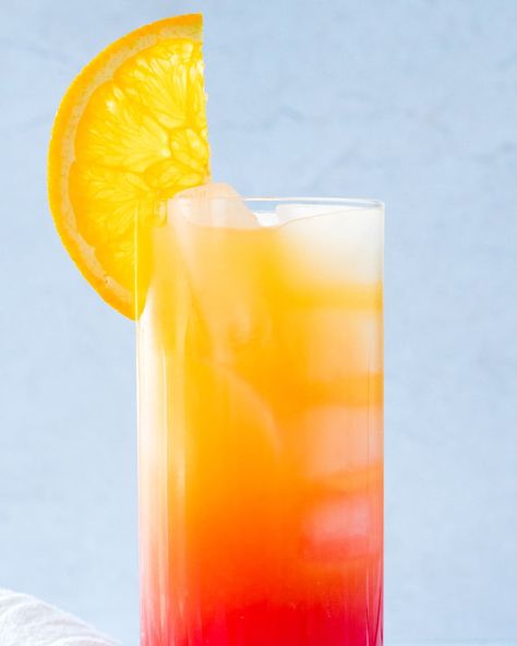 Orange juice, vodka and grenadine layer the colors of a sunrise in the vibrant Vodka Sunrise! Mix up this cocktail to impress. #vodka #vodkasunrise #vodkacocktail #grenadine #orangejuice #orangejuicecocktail #brunchdrink #easycocktail Vodka Sunrise Cocktails, Orange Vodka Cocktails, Sunrise Drink, Dinner Party Drinks, Cocktails Made With Vodka, Drinks Vodka, Vodka Mixed Drinks, Orange Juice Cocktails, Vodka Orange