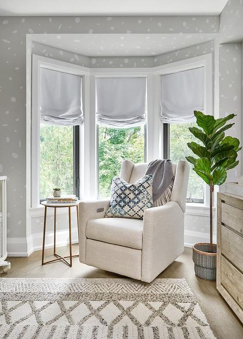 Contemporary nursery with a bay window furnished with an ivory wingback rocker and a fiddle leaf fig plant. White And Gray Curtains, Bow Window Ideas Living Room, How To Decorate A Bay Window, Light Grey Painted Walls, Decorating A Bay Window, Black Curtain Rod, Pink Velvet Curtains, Bay Window Benches, Fiddle Leaf Fig Plant