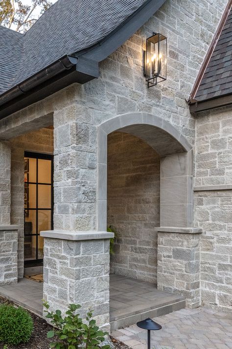 Natural stone luxury dream home features sprawling facade, garage, & front door portico entrance with cut stone accents. The elegance is further enhanced by modern exterior lighting and chandelier, wood backyard decks, outdoor living firepit seating area, and walkway stone pavers. DIY https://www.buechelstone.com/masonry/ how to install stone veneer (mortar / dry stacked stone / exterior & interior stone veneer). Buy stone veneer! Front Door Portico, Grey Stone House, Door Portico, Garage Front Door, Modern Exterior Lighting, Buechel Stone, Stone Exterior Houses, Exterior Houses, Lake Houses Exterior