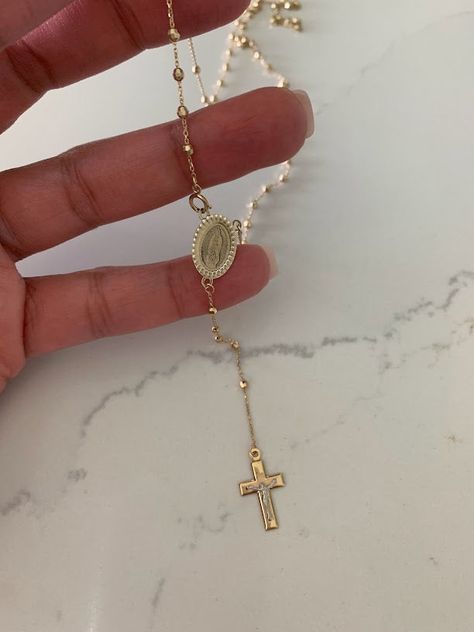 This 14K yellow gold rosary necklace is the perfect religious symbol of faith. Featuring a cross pendant, shiny diamond cut 2.5mm round beads, and a 20” chain, this necklace is a meaningful piece of Catholic jewelry. Its delicate design makes it an ideal gift for anniversaries, confirmations, 1st communion and other special occasions. ♦ Materials: 14K Solid Gold♦ Available colors: Gold ♦ Necklace measurements: 20" total length, beads are 2.5MM♦ Beads measurements: Beads are 2.5MM---------------- Catholic Gold Jewelry, Gold Christian Jewelry, Catholic Cross Necklace, Gold Rosary Necklace, Drops Necklace, Necklace Measurements, Choker Necklace Gold, Catholic Necklace, Beaded Rosary