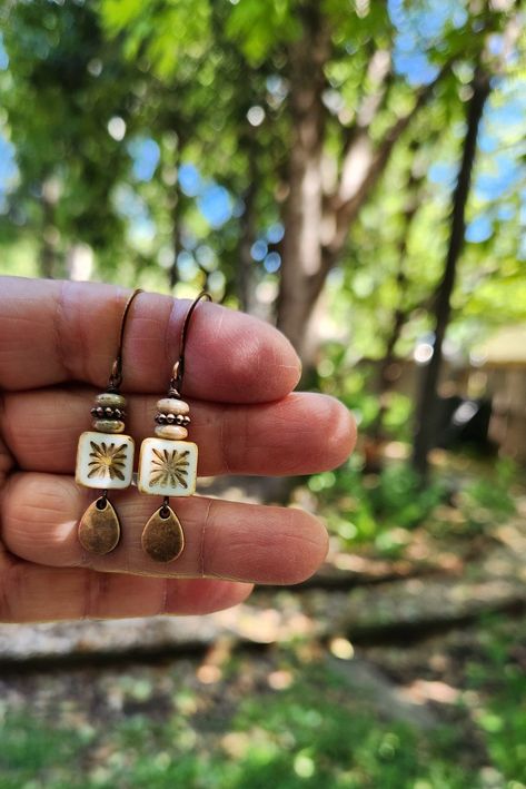 Recent buyer described these earrings as "stunning." The centerpiece for these boho earrings is an Alabaster white tile bead with a gorgeous starburst.  Another petite pair of earrings! Simply gorgeous Czech glass! Love the look! These unique beauties are just under two inches in length, including the copper hooks.  The square tile beads are accented with a stack of luscious mossy green disc beads interspersed with a copper bead.  The whole design is finished off with a lovely dangling copper te Earth Tone Earrings, Czech Glass Earrings, Dopamine Activities, Starburst Tile, Tile Earrings, Artsy Jewelry, Alabaster White, Rustic Earrings, Dangle Earrings Boho