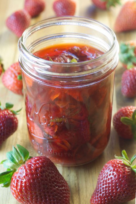 Mason jar filled with strawberry top vinegar with strawberries scattered around the jar. Strawberry Vinegar Recipe, Strawberry Vinegar Uses, Strawberry Tops Vinegar, Strawberry Top Vinegar, Strawberry Vinegarette, Canning Strawberries, Strawberry Balsamic Vinegar, Diy Vinegar, Fruit Vinegar