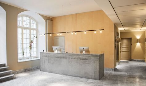 The concrete reception desk. Wingårdh was inspired by Le Corbusier’s Sainte Marie de La Tourette monastery in Lyon, France; the marble and concrete lobby and reception desk, with low lines and brutalist notes, is reminiscent of the concrete structure. Concrete Reception, Wood Reception, Minimalist Maximalist, Transitional Exterior, Transitional Farmhouse, Copenhagen Hotel, Maximalist Interior, Reception Desks, Transitional Bedroom