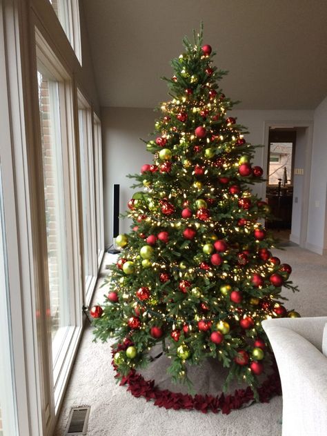 The tree is decorated with red and lime green ball ornaments, both matte and shiny, stuck with paper wrapped wire stems.  The ornaments are not hung from the tree branches in the traditional way. They are laid into and onto the tree as if they were a pick. The balls are next to weightless, so the stiff stems of the tree hold them up. Gold Red Green Christmas Tree, All Green Christmas Tree, Christmas Tree Ideas Red Green Gold, Christmas Decorations Red And Green, Red And Green Christmas Decorations, Green Red And Gold Christmas Tree, Christmas Tree Ideas Red And Green, Red And Green Christmas Tree Decorations, Green Red Christmas Decor