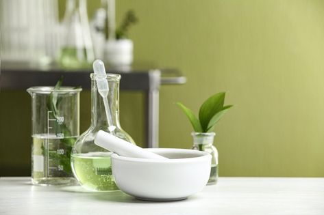 Mortar with pestle and natural ingredients on white table in cosmetic laboratory Cosmetic Laboratory, Cosmetics Laboratory, White Table, Wine Decanter, Matcha, Natural Ingredients, Barware, Lab, Vase