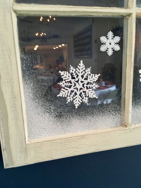 Detail of old window decorated with snowflakes and spray snow. Window Snowflakes Diy, Frosted Windows Christmas, Snow Flake Window Painting, Window Fake Snow Ideas, Snow Window Spray, Fake Snow Window Ideas Spray, Fake Snow On Windows, Christmas Window Snow Spray, Snow On Windows Spray Ideas