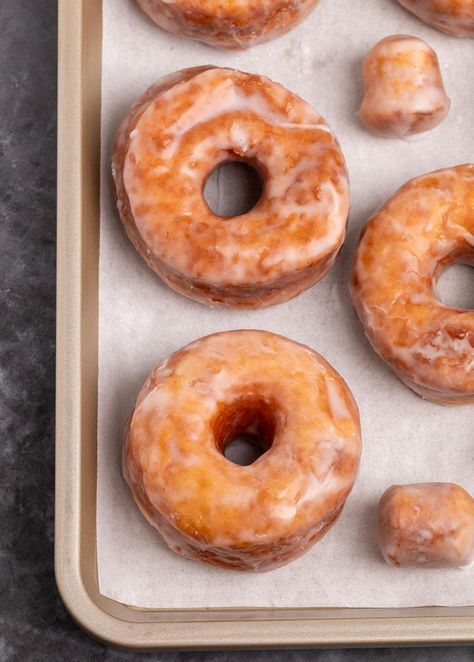 3 brown gluten free donuts with holes with white glaze with 2 glazed donut holes on white paper on gold rimmed baking sheet Gluten Free Long John Donut Recipe, Gluten Free Baked Donut Recipe, Donut Hole Recipe Baked, Glazed Donut Holes, Gluten Free Donut, Gluten Free Donuts Baked, Gluten Free Donut Recipe, Gingerbread Donuts, Raised Donuts