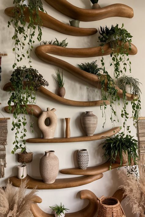 Design a Boho-chic statement wall using organic wooden shelving. Complement the warm tones with cascading plants, earthy textures, and sculptural details to create a harmonious, inviting space. #WoodenShelving #StatementWall #BohoHomeDecor #OrganicDesign #CascadingPlants #EarthyCharm #WovenAccents #GreeneryInspiration #InteriorStyling #DecorGoals Earthy Shelf Decor, Natural Home Decor Ideas, Curved Wall Decor Ideas, Earthy Decorations, Wood Accents In Home, Earthy Apartment Aesthetic, Earth Tone Apartment, Earth Tone Interior Design, Modern Earthy Home Decor