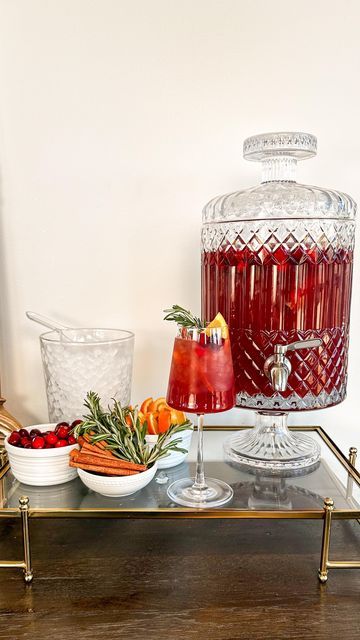 Samantha Bauchmann on Instagram: "LARGE BATCH HOLIDAY RUM PUNCH // the perfect addition to any holiday/christmas/New Years party you’re throwing in the next few weeks! INGREDIENTS: 72 oz 100% cranberry juice 24 oz orange juice 24 oz apple cider 24 oz orange liquor 36 oz spiced rum Garnishes - cranberries, orange slices, cinnamon sticks, rosemary springs INSTRUCTIONS: 1) combine cranberry juice, orange juice, apple cider, orange liquor and spiced rum in large drink dispenser (mine holds 200 oz). Add cranberries, orange slices and cinnamon sticks to top for garnish. 2) Setting up station, add small bowls of garnishes + bowl for ice. Fill wine glass with ice, add punch and garnishes. Serve and enjoy! #cocktails #holidayparty #hosting #easyrecipe" Drink Station Christmas, Drink Dispenser Cocktails, Christmas Drink Dispenser, Large Drink Dispenser, Holiday Rum Punch, Xmas Cocktail Party, Samantha Bauchmann, Xmas Cocktails, Sangria Drink