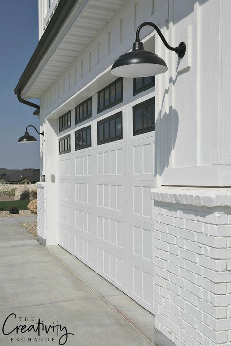 Modern farmhouse exterior lighting. White painted brick, white garage door, black detail and lighting. #exteriordesign White Garage Doors, Farmhouse Garage, Modern Garage Doors, Farmhouse Exterior Design, Garage Door Design, Modern Garage, Brick Exterior House, Modern Farmhouse Exterior, Garage Lighting