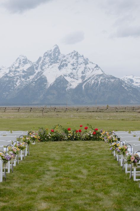 The Grand Teton Mountains lay behind a wedding ceremony with a floral ground installation and aisle of spring flowers. Simple Colorado Wedding, Jackson Hole Wyoming Wedding Venues, Colorado Wedding Ceremony, Montana Outdoor Wedding, Wedding In Glacier National Park, Wyoming Wedding Jackson Hole, Elope Jackson Hole, National Parks To Get Married In, Wedding In The Mountains Colorado