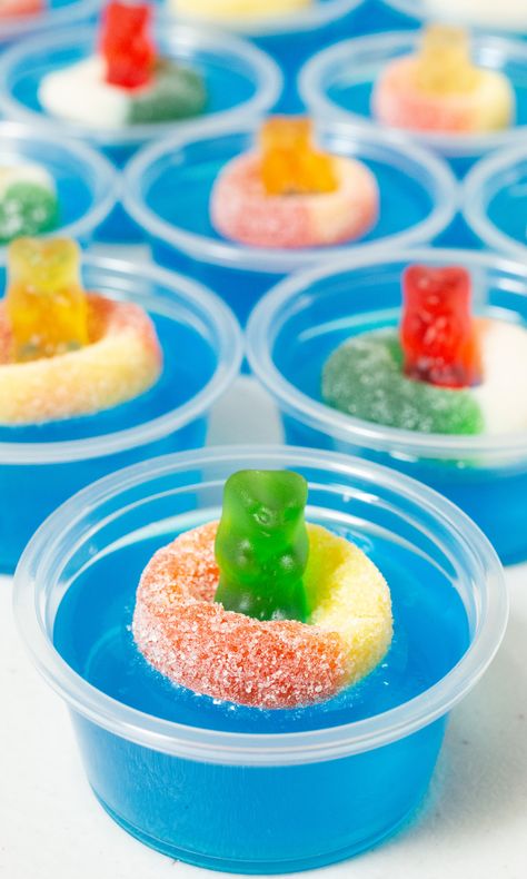 9 2oz plastic containers filled with bright blue jello topped with a candy gummy bear and gummy ring. Pool Party Jello Shots, Jello Shots With Vodka, Party Jello Shots, Shots With Vodka, Vodka Gummy Bears, 34 Birthday, Jello Shots Vodka, Boat Snacks, Jello Cups