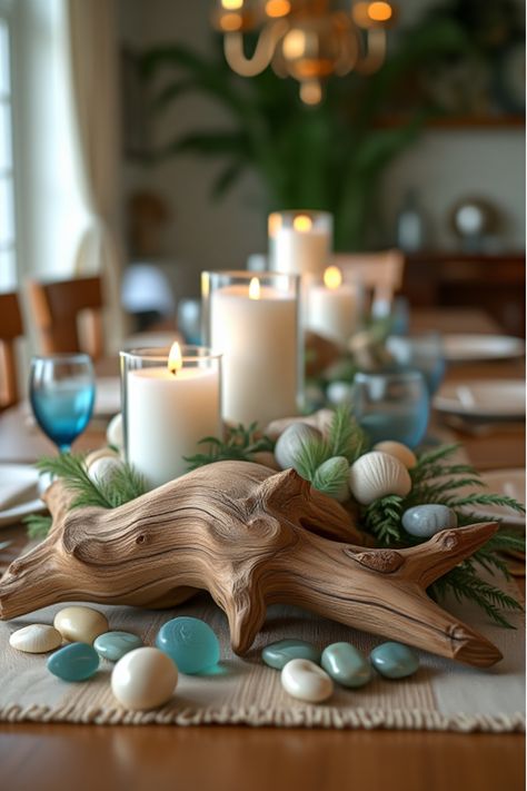 Coastal-themed centerpiece with driftwood, shells, and hurricane candle holders Coastal Dining Table Centerpiece Everyday, Coastal Dining Table Decor, Coastal Centerpiece Dining Table, Beach House Table Centerpiece, Coastal Table Decor Centerpieces, Nautical Dining Table Centerpiece, Farmhouse Centerpiece Ideas, Coastal Centerpiece Ideas, Beachy Candle Center Piece