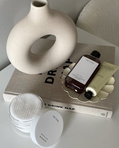 A bedside table with a funky vase resting on a stack of books. There’s a glass dishes filled with perfume bottles and cotton pads in a plastic container off to the side. Insta Content Ideas Lifestyle, Skincare Lifestyle Aesthetic, Skin Care Room Decor, Beige Skincare Aesthetic, Beauty Product Photoshoot Ideas, Ugc Content Aesthetic, Self Care Photoshoot Ideas, Ugc Content Creator Aesthetic, Luxury Self Care Aesthetic