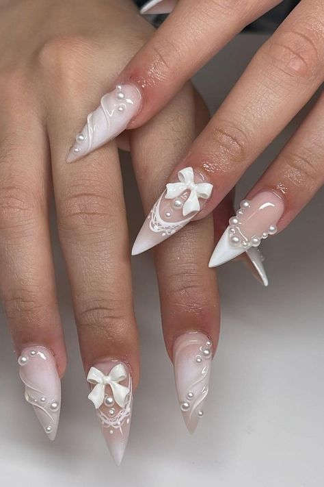 Discover the epitome of elegance with these exquisite white stiletto nails adorned with pearl embellishments and delicate 3D bows. The soft ombre transition from pale pink to white, coupled with intricate lace designs, creates a stunningly feminine look. Click through to explore the entire collection and embrace unmatched sophistication. // Photo Credit: Instagram @nailsbyalyk Stilleto Nails Designs, Chic Nail Art, May Nails, White Acrylic Nails, Really Cute Nails, White Nail, Funky Nails, Chic Nails, Creative Nails