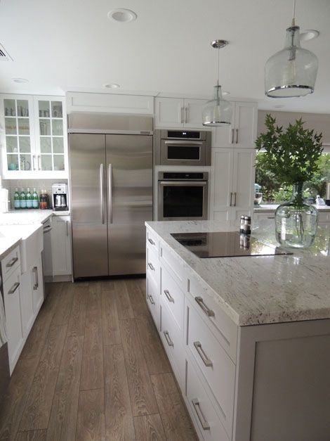 L-shaped kitchen centers on an expansive kitchen island painted Sherwin Williams Dorian Gray topped with a River White Granite counter which frames a GE Monogram 30" Induction Cooktop below a pair of Ballard Designs Addie Pendants. Charlie Anderson, Kitchen Layouts With Island, Kabinet Dapur, Kitchen Wall Colors, Farmhouse Kitchen Design, Kitchen Designs Layout, Kitchen Corner, Kitchen Redo, Trendy Kitchen