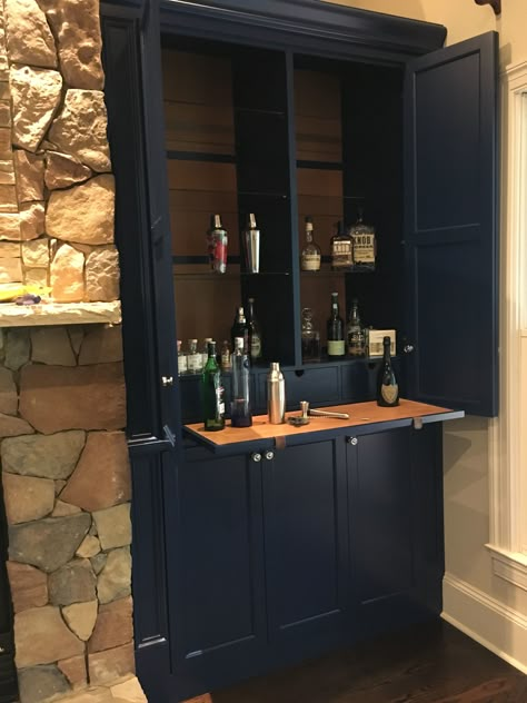 Dry bar in cabinet next to fireplace. Complete with leather pull out shelf, apothecary drawers, pull outs in the lower cabinet, space for an icemaker, glass shelves, leather back panels and LED lights. Bar In Cabinet, Cabinet Next To Fireplace, Built In Bar Cabinet, Blue Fireplace, Apothecary Drawers, Diy Shelf Decor, Pull Out Shelf, Wine Glass Shelf, Glass Shelves Decor