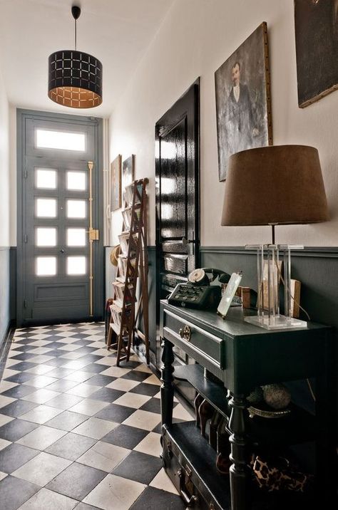 A black and white entryway with a black vintage console table, a ladder for storage, a pendant and a floor lamp and an artwork Black And White Entryway, White Foyer, Black French Doors, Cool Chandeliers, White Entryway, Vintage Console Table, Vintage Console, Black Accent Walls, White Marble Floor