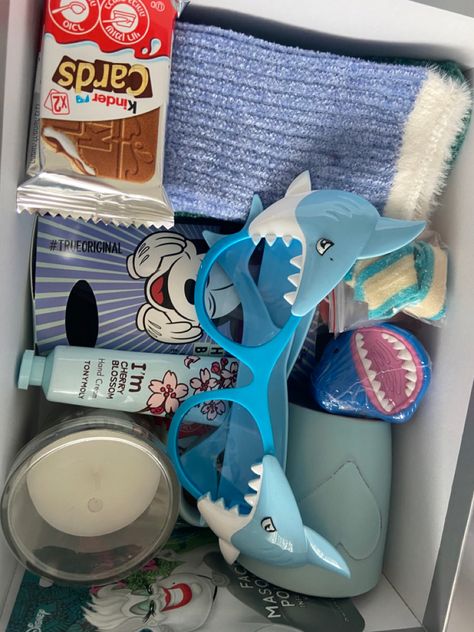 blue heart mug, candle, blue and green socks, shark glasses, hand cream, Ursula face mask (the little mermaid),  Mickey mouse headband and shark candy 🦈💙🤍 Gifts For Shark Lovers, Shark Gift Basket, Shark Presents, Gift Theme Ideas, Shark Gift Ideas, Valentine Gifts For Boyfriend, Diy Valentine Gifts For Boyfriend, Best Friend Birthday Present, Shark Themed Birthday