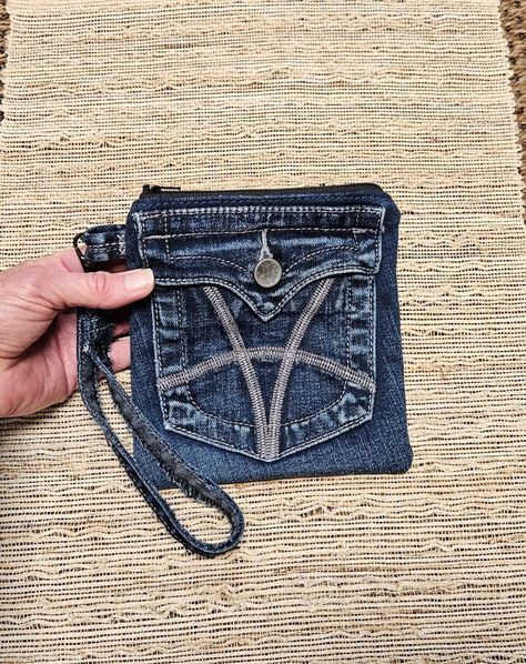 This stylish denim pocket coin pouch wristlet was created from a blue denim pocket from a pair of KUT brand jeans.  There is a button closure pocket on the front, outside of the pouch, and a zipper closure on the bag itself.  This jeans coin pouch is lined with a gray paisley pattern cotton fabric liner.  There is a removeable wrist/wristlet strap with gunmetal (metal) lobster swivel clasp, which I've made from a leg seam from the same pair of jeans, included. This denim zipper pouch measures 6.5 inches tall, and 6 inches wide.  The removeable wrist strap measures 7 inches. The cotton liner material has been prewashed and dried on low heat, so this denim bag is machine washable, preferably dried on low heat, or hang to dry. Please note, the denim material is previously worn, and may have s Rectangular Denim Bag With Zipper Pouch, Denim Bags With Removable Pouch, Jean Pocket Purse, Blue Recycled Denim Bag With Zipper Pocket, Denim Wristlet, Denim Blue Bags With Zipper Pocket For On-the-go, Blue Recycled Denim Shoulder Bag With Zipper Pocket, Denim Clutch, Jean Purses