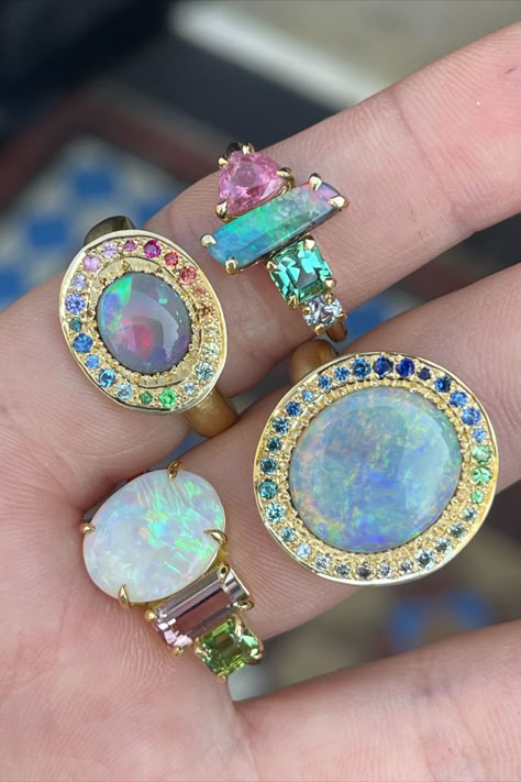 Close-up of four yellow-gold rings, worn on the inside of two fingers. Each ring features an opal as the main gemstone, with multicoloured surrounding and side stones. Opal Stone Jewelry, Types Of Opal Stones, Modern Opal Jewelry, Wedding Ring Upgrade, Weird Accessories, Large Engagement Rings, Antique Opal Ring, Gold Opal Ring, Rings To Make