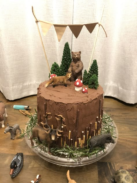 Chocolate cake with woodland animals, fondant toadstools, trees and bunting. It's a three tier classic chocolate cake from BBC Good Food. Covered in butter icing and decorated with Schleich animals, Mikado biscuits and artificial trees. The bunting is homemade from Kraft paper, twine and bamboo skewers. The greenery is rosemary from my herb garden. Woodland Birthday Cake, Forest Birthday Party, Baby Shower Decorations Neutral, Animal Birthday Cakes, Baby Proof, Woodland Cake, Forest Birthday, Woodland Birthday Party, Baby Shower Woodland Theme