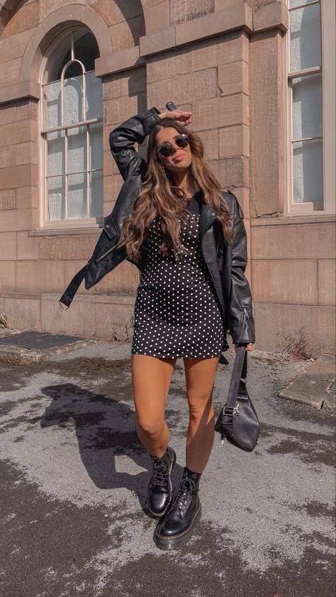 Girl wearing an oversized leather jacket, a black polka dot dress , sunglasses and docs Leather Skirt Outfit With Doc Martens, Leather Jacket Dress Boots, Oversized Leather Jacket Outfits Night Out, Dr Martens Night Out Outfit, Night Out Outfit Doc Martens, Black Dock Martins Outfits, Romper With Doc Martens, Doc Martin Shorts Outfit, Dress Outfits With Doc Martens