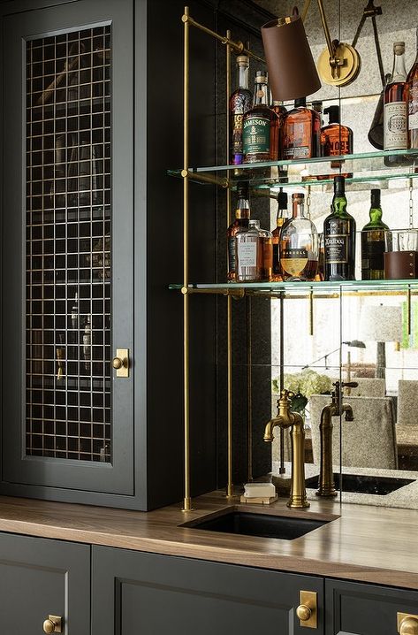 Beautifully appointed wet bar boasts glass and brass shelves fixed in front of a mirrored backsplash and over a small black sink with an antique brass faucet. Brass Bar Shelves, Glass Bar Shelves, Antique Mirror Backsplash, Wet Bar Cabinets, Wet Bar Sink, Bistro Shelving, Jean Stoffer Design, Wet Bar Designs, Bar Nook