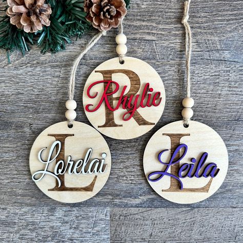 "This simple, minimalist ornament will be a perfect addition to any Christmas theme.  Can also be used as a gift tag. Ornaments are 3.25\" in diameter, and approx. 1/4\" thick.  The initial is stained on the first layer,  with the name as an additional layer, giving the ornament dimension. Choose text color, and enter your desired text in the personalization area." Layered Wood Christmas Ornaments, Personalised Ornaments Christmas, Personalized Wooden Ornaments, Personalized Wood Ornaments, Laser Engraving Acrylic Ideas, Christmas Laser Ideas, Laser Engraved Christmas Ornaments, Laser Christmas Ornaments, Laser Wood Projects