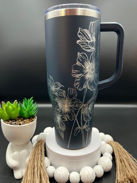 Wildflowers Floral Laser Engraved 40oz Tumbler with Handle Lid and Straw, Custom Engraved Seamless Tumbler, Double Wall Insulated Cup This custom engraved 40oz Powder Coated Double Wall Insulated tumbler with handle and leak proof lid keeps you beverage at the perfect temperature for hours!  **TUMBLER IN PHOTO IS TO ILLUSTRATE THE DESIGN OPTION.  IT MAY BE SHOWN ON A BRAND     TUMBLER BUT DOES NOT REPRESENT THE TUMBLER YOU WILL RECEIVE.  IF YOU ORDER NON     BRANDED, YOU WILL RECEIVE A NON BRAND Laser Engraving Cups, Etched Stanley Cup, Engraved Tumbler Designs, Laser Engraved Cups, Laser Engraved Tumblers, Engraved Tumbler Ideas, Stanley Ideas, Etched Tumblers, Yeti Cup Designs