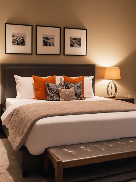 Cozy bedroom with a plush king-sized bed, dressed in crisp white linens and a soft, tan throw blanket. The headboard is upholstered in charcoal gray fabric and accented with three black and white patterned throw pillows and two burnt orange pillows. The room is further adorned with three black and white framed photographs hanging above the headboard. The soft lighting and neutral color scheme create a relaxing and inviting atmosphere. Burnt Orange And White Bedroom, Black White Tan Bedroom, Tan Throw Blanket, Tan Bedroom, Burnt Orange Pillows, Orange Rooms, Orange Pillows, Neutral Color Scheme, Spare Room