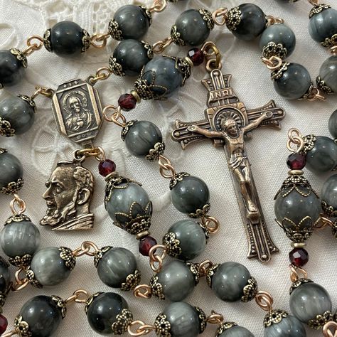 A wonderful handmade rosary honoring the humility, reverence and intense devotion  of St. Padre Pio of Pietrelcina, who was himself dedicated to the meditations of the rosary.  The elegant Art Deco Crucifix and coordinating two-sided Sacred Heart of Jesus / Holy Mother Centerpiece are solid bronze replicas,  hand cast in the USA from antique pieces, giving the rosary an Old-World grace.   An additional bronze medal of St. Padre Pio hangs below the centerpiece.   The Ave beads are satiny smooth, Rosary Ideas, Rosary Prayers Catholic, Rosary Making, St Padre Pio, Handmade Rosary, Rosary Prayer, Sacred Heart Of Jesus, The Rosary, Heart Of Jesus