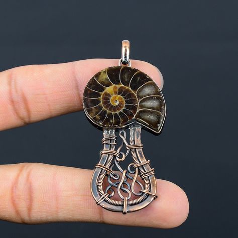 Welcome to our little shop, where you can find handmade copper wire jewelry and more, for you and your loved ones. We do accept custom orders also, kindly message us for more. Ammonite Fossil Gemstone Copper Wire Wrapped Handmade Pendant A copper I wrapped on a beautiful Ammonite Fossil Gemstone . Size May Be slight Differ Than Shown In The Picture Gemstone : Ammonite Fossil  Metal : Copper  * Protection:- Copper will be tarnished after a while so try to limit contact with lotions, soaps or anything moist and never wear it in the shower, swimming or anywhere else it may come in contact with water. If tarnish becomes an issue, you may clean this item with jewelry cleaning cloth or ultra polishing pads. * Packing:- Your jewelry arrived in a beautiful gift box stored in bubble wrap for safe t Wire Wrapped Mushroom, Copper Wire Jewelry, Copper Jewelry Handmade, Fossil Jewelry, Ammonite Fossil, Handmade Jewelry Gift, Handmade Copper, Handmade Pendant, Chain Pendant