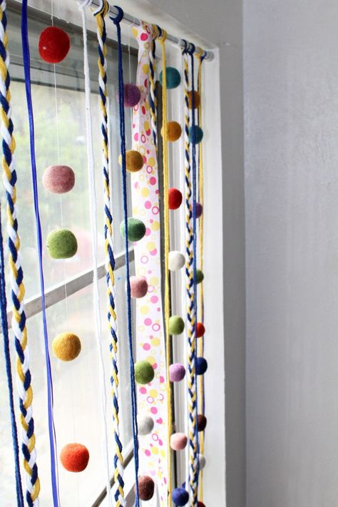 Make a fun and funky window hanging to dress up your home decor for spring. This DiY is easy to make with a combination of yarn, ribbon, and felt balls - or whatever scrap craft materials you have lying around. Comfy Decor, Boho Tent, Diy Spring Crafts, Hanger Ideas, Window Hanger, Warm Home Decor, Flower Curtain, Family Wall Decor, Funky Home Decor