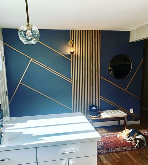 Wooden slats used as asymmetrical design on a blue grey painted wall in the entry way. Brass minimalist light fixture and a round brass mirror. Blue Gold Accent Wall, Blue Slat Wall, Navy Slat Wall, Dark Blue Wall With Wood Accent, Navy Blue Slat Wall, Blue And Gold Accent Wall, Slat Entryway, Blue Wall Gold Accents, Spa Inspired Bedroom