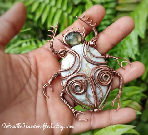 I am holding a Beetle Pendant Wire Wrap Created with White Jasper stone and green Labradorite in Copper Wires. The background is green fern plant Wire Beetle, Wire Insects, Custom Beetle, Beetle Jewelry, Beetle Pendant, Beetle Necklace, Insect Necklace, Wire Wrap Jewelry Designs, Beetle Insect