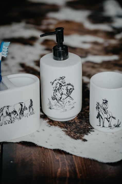 We can't get enough of the western scenic 'Ranch Life' home decor collection and are excited to add to it a bathroom countertop set! Made from ceramic in a classic and versatile black and white colour way, the 3 piece set features working cowboys, bucking broncos, and grazing remuda and will bring western flare to your bathroom while serving a vital purpose! Store your soap, toothbrushes, and more with this 3 piece set that also includes a tumbler. 3 piece set (tumbler, Soap/lotion dispenser, to Cowboy Bathroom Ideas, Western Themed Bathroom, Western Bathroom Ideas Rustic, Small Western Bathroom Ideas, Western Home Decor Diy, Western Bathroom Ideas, Western House Decor, Farmhouse Western Decor, Boho Western Bathroom