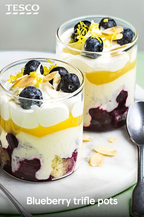 Our blueberry trifle pots are the perfect pudding for April. Layer homemade blueberry compote with whipped cream, ready-made lemon cake and lemon curd, then top with toasted almonds. This is one for all those fruity dessert fans out there. | Tesco Lemon Curd Trifle, Lemon Blueberry Trifle, Mini Trifles, Lemon Trifle, Blueberry Trifle, Dessert Pots, English Trifle, Icebox Cakes, Fruity Dessert