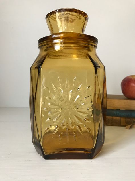 "Vintage Amber Wheaton Glass Canister Jar Amber colored Wheaton glass jar with lid. It has a snowflake or sunburst design on the front and back and on the top of the lid. The perfect accent in a mid century, retro, 70's kitchen decor. Good condition with normal age related wear. I do not see any chips or cracks. Please view all the pictures as they are part of my description and show the condition of this item. Measures: 10\" tall 5 1/2\" wide at the bottom" Vintage Glass Jars, Glass Jar Aesthetic, Large Glass Jar Decor, Jar Design Ideas, Aesthetic Jar, Amber Decor, Vintage Glass Bottles, Unique Jars, Retro Things