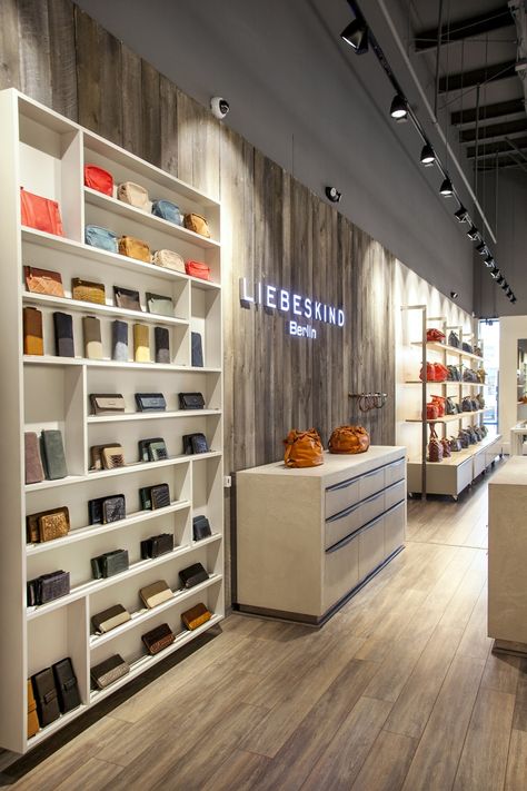 Bag Showroom Display, Retail Power Wall Displays, Long Narrow Retail Space, Contemporary Store Design, Retail Display Fixtures, Bag Store Display Ideas, Shop Flooring Ideas, Store Accent Wall, Bags Store Design