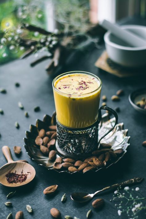 Saffron and cardamom infused almond milk in a Russian tea glass on a table Saffron Drink, Almond Milk Drinks, Badam Milk, Milk Photography, Saffron Flower, Russian Tea, Vegan Cafe, Dessert Photography, Almond Paste