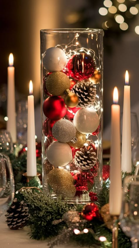 Festive table center with a tall glass vase filled with red, gold, and white ornaments, pinecones, and string lights. Candles create a warm glow. Decor For Christmas Ideas, Cheap Table Decor, Christmas Dinner Centerpieces, Table Decor For Christmas, Xmas Dinner Table, Snowflake Centerpieces, Christmas Wedding Table, Christmas Table Decorations Centerpiece, Decor Ideas For Christmas