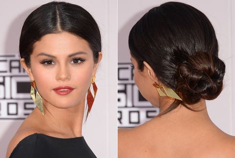 At the 2014 American Music Awards, actress and singer Selena Gomez paired her sleek black gown with a mega-sized 'do perfect for showing off her on-trend center part and oversize gold geometric earrings.  - GoodHousekeeping.com Sock Bun Hairstyles, Center Part Hairstyles, Selena Gomez Hair, Man Bun Hairstyles, Low Bun Hairstyles, Fancy Hair, Center Part, Low Bun, Fancy Hairstyles