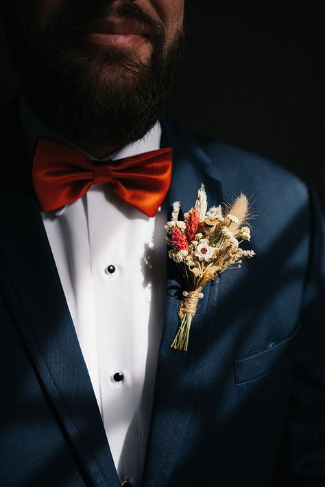 Fall wedding groom wearing burnt orange bowtie with dried floral boutonniere and navy blue suit jacket Navy Blue Suit With Burnt Orange Tie, Navy And Rust Wedding, Navy Groom Suit, Groom Suit Navy, Groom Blue Suit, Navy Groomsmen, Floral Boutonniere, Fall Wedding Style, Navy Wedding Colors