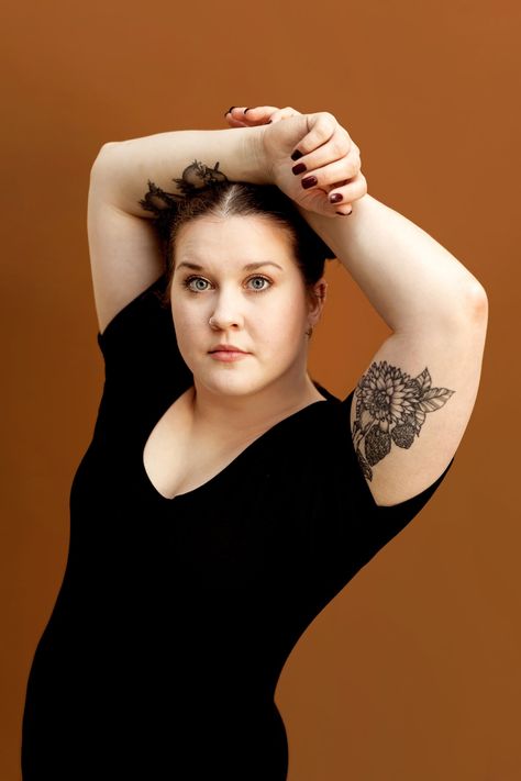 A woman poses with her hands above her head in front of an orange backgroundfor her studio headshot Hands Above Head Pose Reference, Hands Above Head Pose, Hands Behind Head Pose, Studio Headshots, Pulled Back Hairstyles, Headshot Poses, Hair Pulling, Woman Drawing, Female Poses