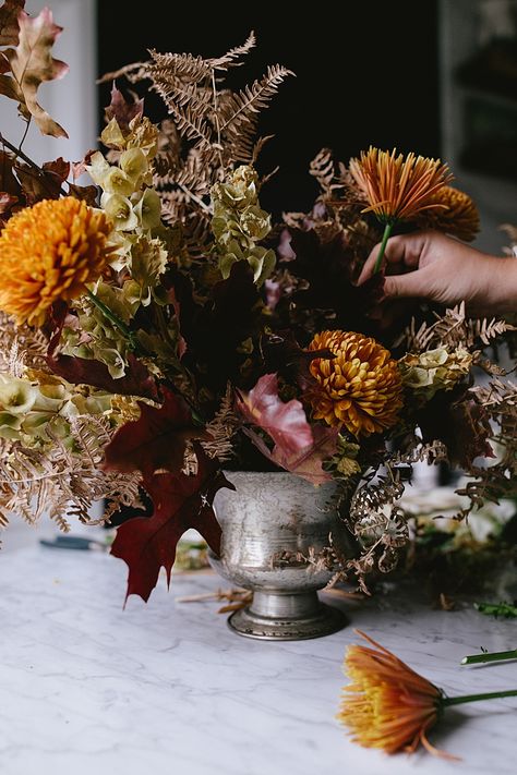 Learn How to Make this Modern Thanksgiving Centerpiece with Dried Flowers, Golden Chrysanthemums, Cream Spray Roses, Branches of oak and maple leaves. Get the full DIY tutorial on Jojotastic.com #flowerarrangement #floralarrangement #flowerarranging #centerpiece #thanksgiving #fall #thanksgivingdecor #florals #flowers #fallflowers #friendsgiving Thanksgiving Flowers Centerpieces, Fall Foliage Arrangements, Diy Thanksgiving Decorations Table, Thanksgiving Floral Centerpieces, Moody Thanksgiving, Thanksgiving Arrangements, Thanksgiving Flower Arrangements, Thanksgiving Floral Arrangements, Thanksgiving Centerpieces Diy