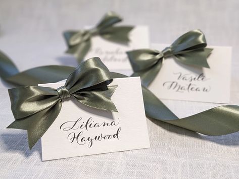 Add elegance and fun to your party or wedding with these bow place cards. The name on each card is hand written in black ink. The bows are hand tied from satin ribbon and attached to the card. Choose from a variety of ribbon colors to compliment the theme or decor of your dinner party, wedding, or other special event. You have the option to indicate meal choice with different ribbon colors if desired. Actual ribbon color may vary slightly due to differences in computer monitor displays. Ribbon is 1 inch wide double sided satin. Place cards are tented white cardstock, 2.5x3.5 inches finished size. Names are written in black ink. If you want a color of ribbon not listed, colored ink, or more than 30 place cards, send me a message and I can create a personalized listing for you. Additional ti Bow Name Place Cards, Place Setting Name Cards, Name Cards Wedding Table, Tea Party Name Place Cards, Bow Place Cards, Place Names Wedding, Place Cards Wedding, Name Cards Wedding, Personalized Bow