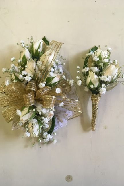 White miniature roses, baby's breath, and green leaves with a gold trim corsage and boutonniere Green And Gold Corsage Prom, Green And Gold Boutonniere, White And Gold Corsage And Boutonniere, Corsage With Green Dress, Corsage Prom Gold, Green And Gold Corsage, White And Gold Boutonniere, Gold And White Corsage, Gold Corsage And Boutonniere