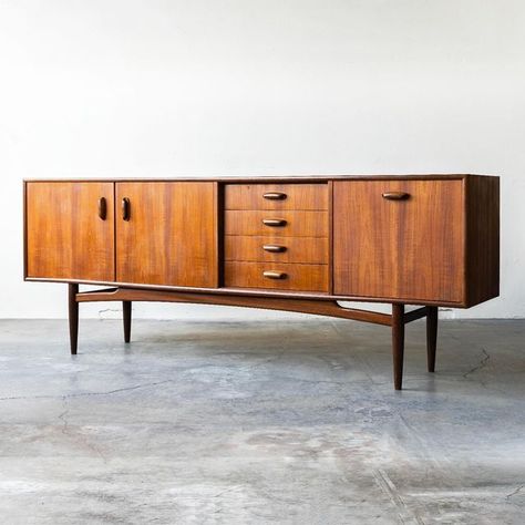 Mid-Century Modern Furniture on Instagram: "G-Plan Fresco, teak, British sideboard designed by V.B. Wilkins.⁠ ⁠ Features:⁠ ⁠ • Beautiful teak woodgrain through-out⁠ • Drop-down bar⁠ • Center drawers⁠ • Doors open to an open fixed shelf⁠ • Model 4058⁠ • Body stands on a frame of turned legs joined by an arched crossbar⁠ • Sculpted teak hardware⁠ • Ample storage⁠ �⁠ Dimensions:⁠ 81“W x 31”H x 18“D⁠ ⁠ Visit the website to learn more and/or to get a shipping quote.⁠ ⁠" G Plan Furniture, Mid Century Sideboard, Teak Sideboard, Sideboard Designs, Door Opener, Mid Century Modern Furniture, Sideboard, Wood Grain, Modern Furniture