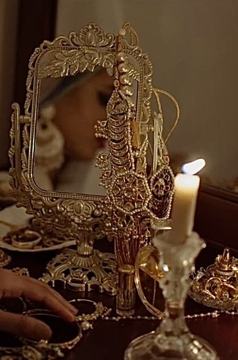 A golden patterned mirror and a lit candle, intricate patterns and jewellery. Golden hyper feminine desi aesthetic Mode Gossip Girl, South Asian Aesthetic, Deep Voice, Pakistani Culture, Bridal Photography Poses, Indian Princess, Royalty Aesthetic, Royal Aesthetic, Indian Photoshoot